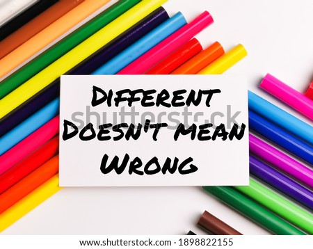Text DIFFERENT DOES NOT MEAN WRONG on paper note with colorful pencils isolated on white background.Motivational quote.