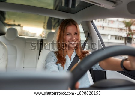 Portrait of smiling young caucasian woman sitting alone on driver seat with fasten belt while driving modern car. Lifestyle and success concept Royalty-Free Stock Photo #1898828155