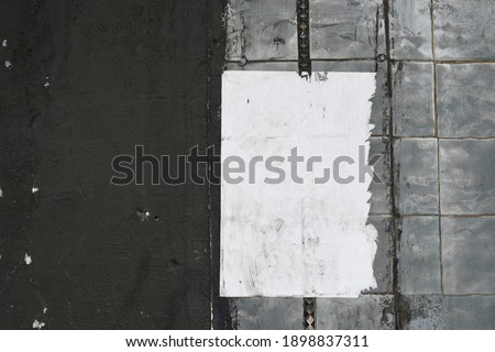 Old abandoned warehouse wall with old tiles and ripped worn shabby paper note