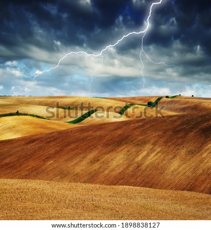 lightning over a hilly field. landscape with dramatic thunderclouds in the background