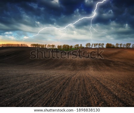 lightning over a hilly field. landscape with dramatic thunderclouds in the background