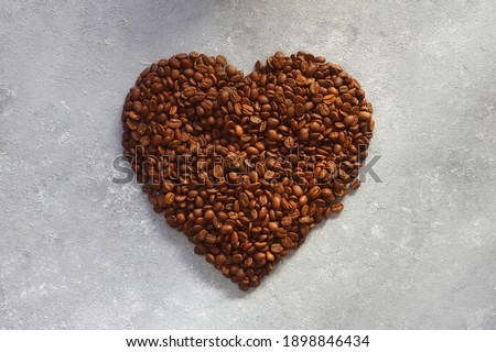 Heart shape made of coffee beans on stone background. Concept of Love to coffee.