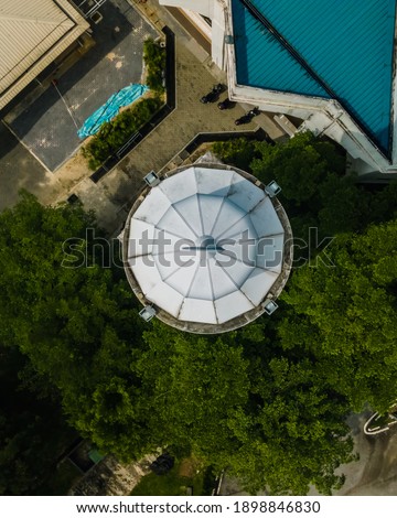 An aerial photo top down of a tower building next to the Tuanku Mizan Zainal Abidin Mosque.