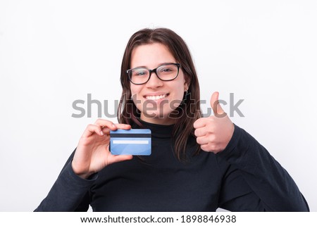 Joyful young woman showing thumb up and blue credit card