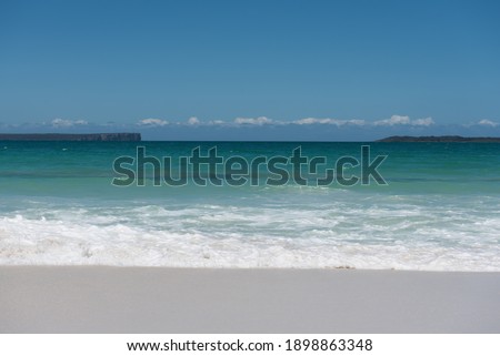 White sandy beach with a deep blue ocean and a clear sky as a background in a bright sunset