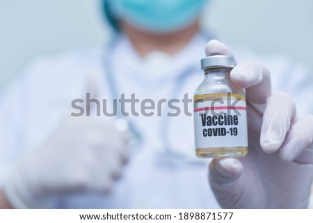 Doctor holding Covid-19 vaccine vial-Medicine and showing thumbs up.-pharmaceutical research and health care concept.