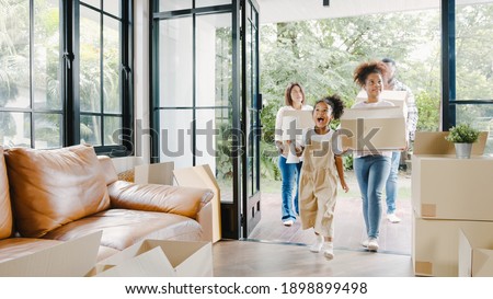 Happy African American young family bought new house. Mom, Dad, and child smiling happy hold cardboard boxes for move object walking into big modern home. New real estate dwelling, loan and mortgage. Royalty-Free Stock Photo #1898899498