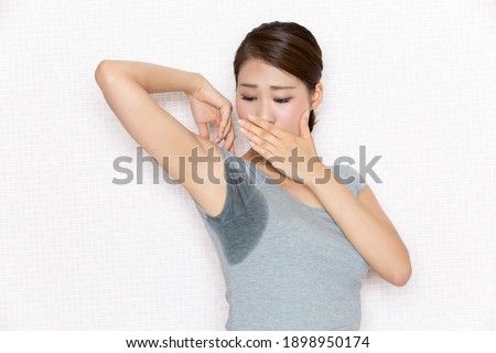 A woman is surprised to see her armpit sweat. Royalty-Free Stock Photo #1898950174