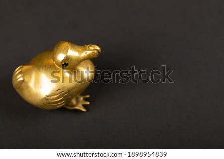 Close up picture of little gold figurine of animals on black background