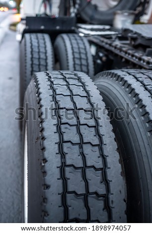 Large tread with grooves and special pattern for durable traction on big rig semi truck tractor tires on paired wheels ensures safe grip when transporting heavy cargo at any weather condition