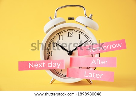 Procrastination, delay and postpone concept. Alarm clock with sticky notes   later, tomorrow, next day and after on the yellow background Royalty-Free Stock Photo #1898980048