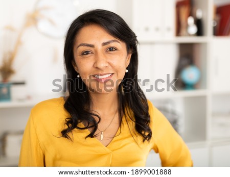 Happy smiling Latin American businesswoman standing in office and looking at camera Royalty-Free Stock Photo #1899001888