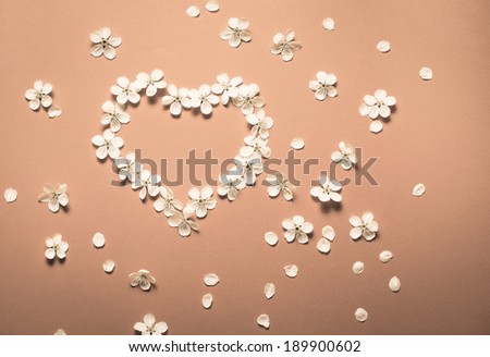 Heart as a symbol of love made of flowers on pink background.