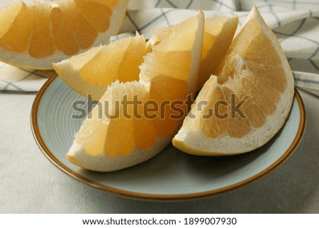 Kitchen towel and plate with pomelo slices on white textured background