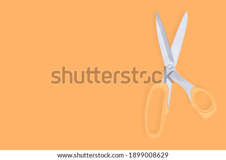 Barber scissors against orange background backdrop.