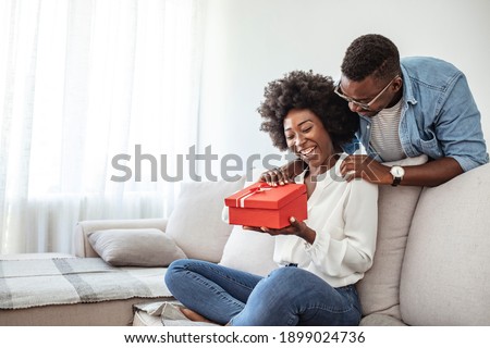 Young couple with gift box hugging at home. Valentine's Day concept. Happy couple in love with. A young loving couple celebrating Valentine's Day at the home. Lovers give each other gifts. Romance
