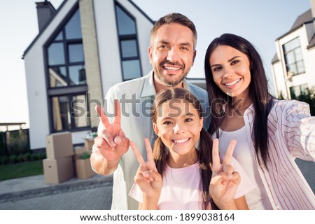 Photo portrait of happy family and small daughter showing v-sign smiling spending time together outside new home