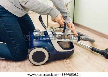 Woman takes dust filter out of vacuum cleaner at home. Container full of dirt. Household chores. Modern equipment Royalty-Free Stock Photo #1899050824