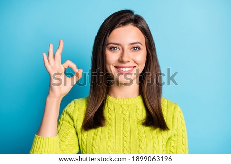 Portrait of young attractive smiling positive good mood happy girl woman female showing sign okay isolated on blue color background