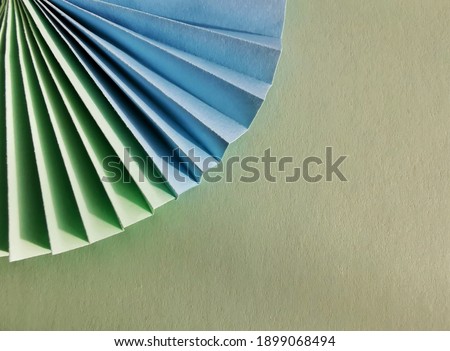 Green and blue circle shape of origami papers on green background. Background texture. Flat lay. 