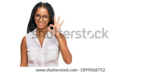 Beautiful hispanic woman wearing casual clothes and glasses smiling positive doing ok sign with hand and fingers. successful expression. 