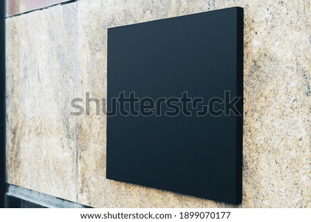 Black square sign with blank space for your logo on the marble wall of a modern business center, mock up
