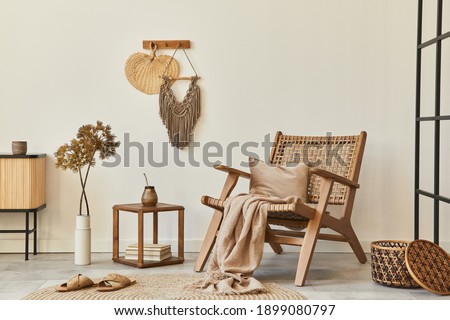Stylish interior design of living room with wooden armchair, coffee table, furniture, rattan decoration, dried flowers and elegant personal accessories. Copy space white wall. Template.