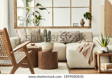 Interior design of living room with stylish modular beige sofa, wooden coffee tables, plants, pillows, plaid, neutral room divider, decoration and elegant accessories. Modern home decor. Template. Royalty-Free Stock Photo #1899080830