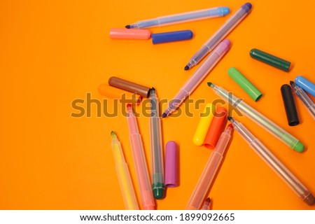 
Lots of bright, colored pencils on a orange background full screen.