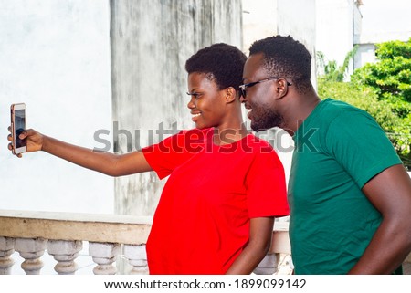 beautiful young happy couple taking photo on mobile phone on the balcony of the house while smiling.