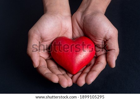  Close up on hands holding a red heart, black bakground