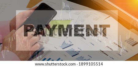 The businessman on the left in a pink shirt sits in his hands with a phone against the background of a financial chart and makes payment.