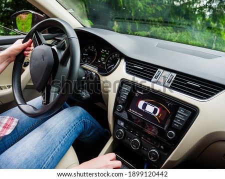 view inside modern luxury car with female woman driving inside making reverse maneuver park assist parktronic showing the obstacles on the main screen display Royalty-Free Stock Photo #1899120442