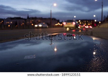 reflections of lights in a puddle in the center of prague after rain in the background blurred cars