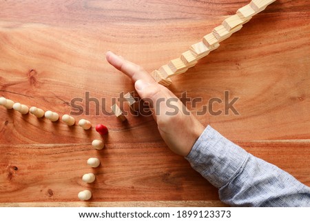 image of male hand stopping the domino effect. executive and risk control concept