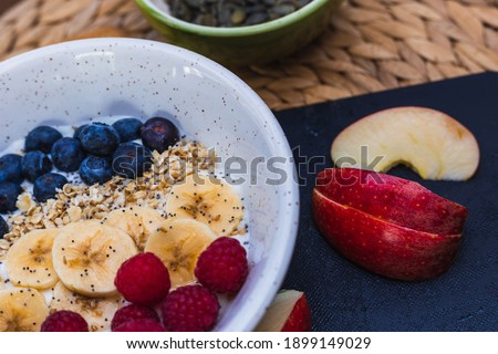 Close up picture of a Bowl of fruits, with sliced apples in the right side, a white bowl and a brown background