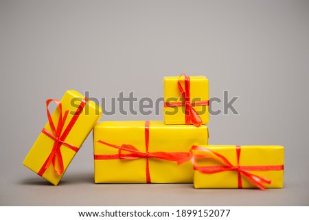 wrapped yellow presents with red ribbons on grey