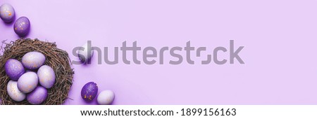 Easter eggs in nest on purple background. Flat lay, top view. Royalty-Free Stock Photo #1899156163