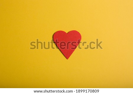One paper heart on yellow background.