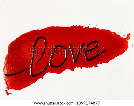 the word love is black glossy paint on a smear of red .love  backgrounds. Oil paint