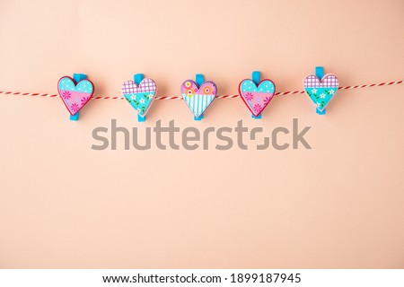 Wooden clothespin with small hearts on the pastel background, copy space