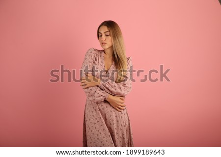 Young woman in dress on pink background