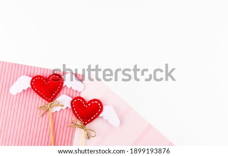 Background Is Valentine's Day. Two hearts with handmade wings on a white background with pink paper