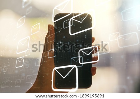Double exposure of postal envelopes hologram and hand with cell phone on background. Electronic mail and spam concept
