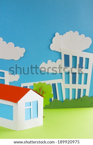 Paper cottage over city background real estate concept