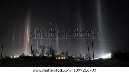 
Night photo of the village, beams of searchlights in the cold. Artificial northern lights.