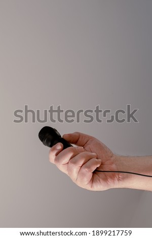 A man's hand holding a black microphone. Concept of communication, interviews, virtual dialogues.