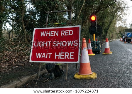 Traffic works sign saying when red light shows wait here with traffic cones