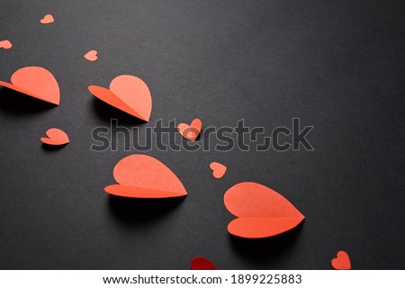 Valentine day decor. Red paper hearts on black background. Red hearts - a symbol of love