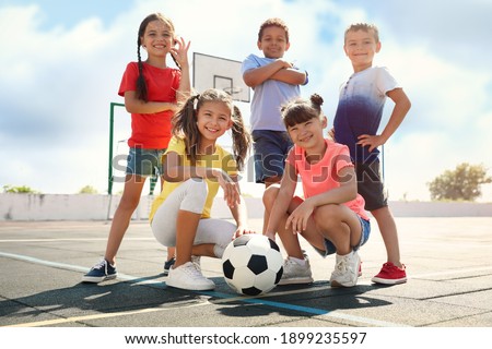 Cute children with soccer ball at sports court on sunny day. Summer camp Royalty-Free Stock Photo #1899235597
